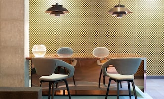 Un interior moderno con una pared con estampado, dos lámparas colgantes y dos sillas con una mesa de vidrio.