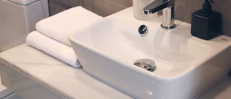 A bathroom with a white sink, a black soap dispenser, and a glass container on the countertop.