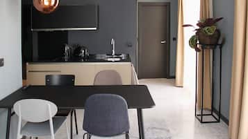 Een moderne keuken met een zwart aanrecht, een koperen hanglamp en een deur die naar een andere kamer leidt.