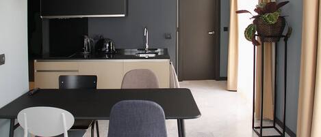 A modern kitchen with a black countertop, a copper pendant light, and a door leading to another room.