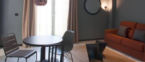 Una sala de estar moderna con una mesa redonda, dos sillas, un sofá y una lámpara de pie.