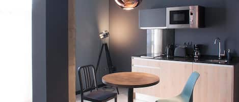 Una cocina moderna con una mesa redonda de madera, dos sillas, una lámpara colgante y un microondas empotrado.