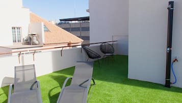 Eine Dachterrasse mit Kunstgras, zwei Liegestühlen, einem kleinen Tisch und einer Wasserpfeife.