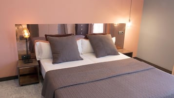 Een hotelkamer met een bed, twee nachtkastjes, een lamp en een wandlamp.