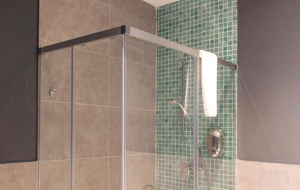 A glass-enclosed shower area with a metal frame, a handheld showerhead, and a wall-mounted towel rack. - Be Mate Málaga Soho (Málaga)
