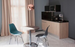 A modern kitchen with a microwave, coffee machine, and a sink. There are two chairs and a round table in the dining area. - Be Mate Málaga Soho (Málaga)