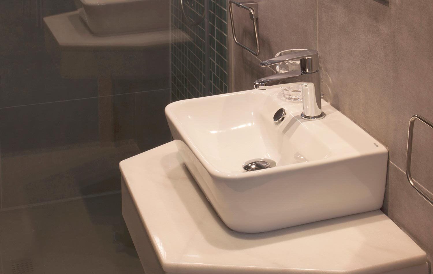 Un baño moderno con lavamanos blanco, grifo cromado y cabina de ducha de vidrio.