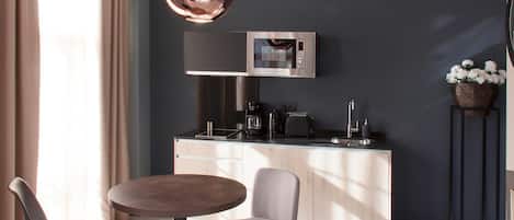 A modern kitchen with a built-in microwave, a coffee maker, and a toaster. There is a round table with two chairs and a large mirror above it.
