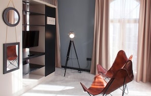 A modern room with a black shelving unit, a mounted television, a tripod lamp, and a leather chair.