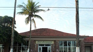 A hotel named "Hotel Harmony" with a red-tiled roof, large windows, and palm trees in front. - Hotel H Itanhaém (Itanhaém)