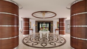 Eine Lobby mit einem runden Tisch in der Mitte, flankiert von großen Holzsäulen, und einem Muster im Boden.