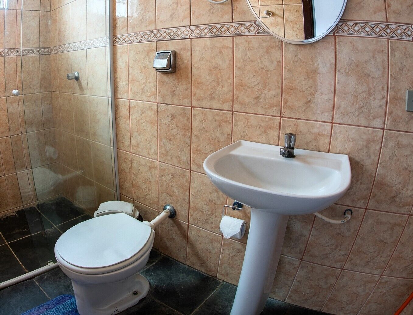 Un baño con inodoro, lavabo y zona de ducha.