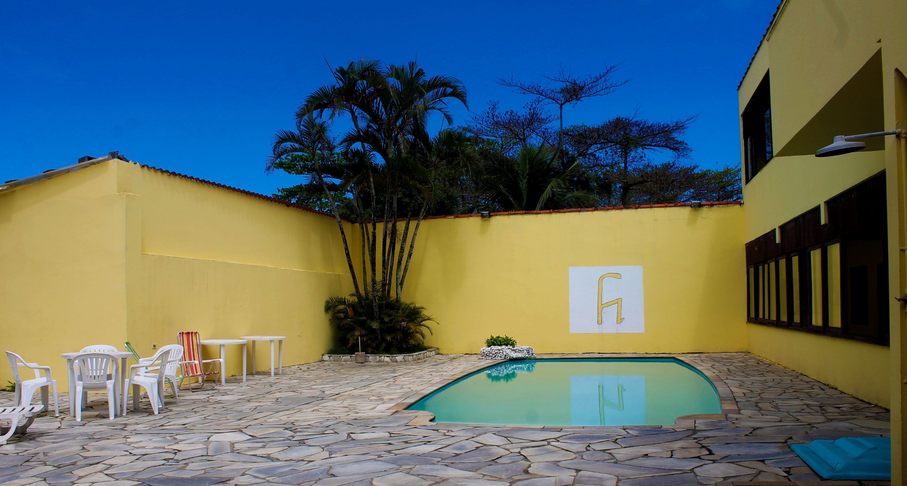 Une cour avec une piscine, des murs jaunes et du mobilier d’extérieur.