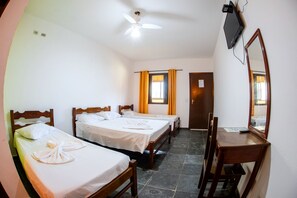 Une chambre d’hôtel avec deux lits simples, un bureau avec une chaise, un ventilateur de plafond, un téléviseur fixé au mur et une fenêtre avec des rideaux.