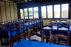 Un restaurant doté de nombreuses tables et chaises, de grandes fenêtres et offrant une vue sur les voitures garées à l’extérieur.