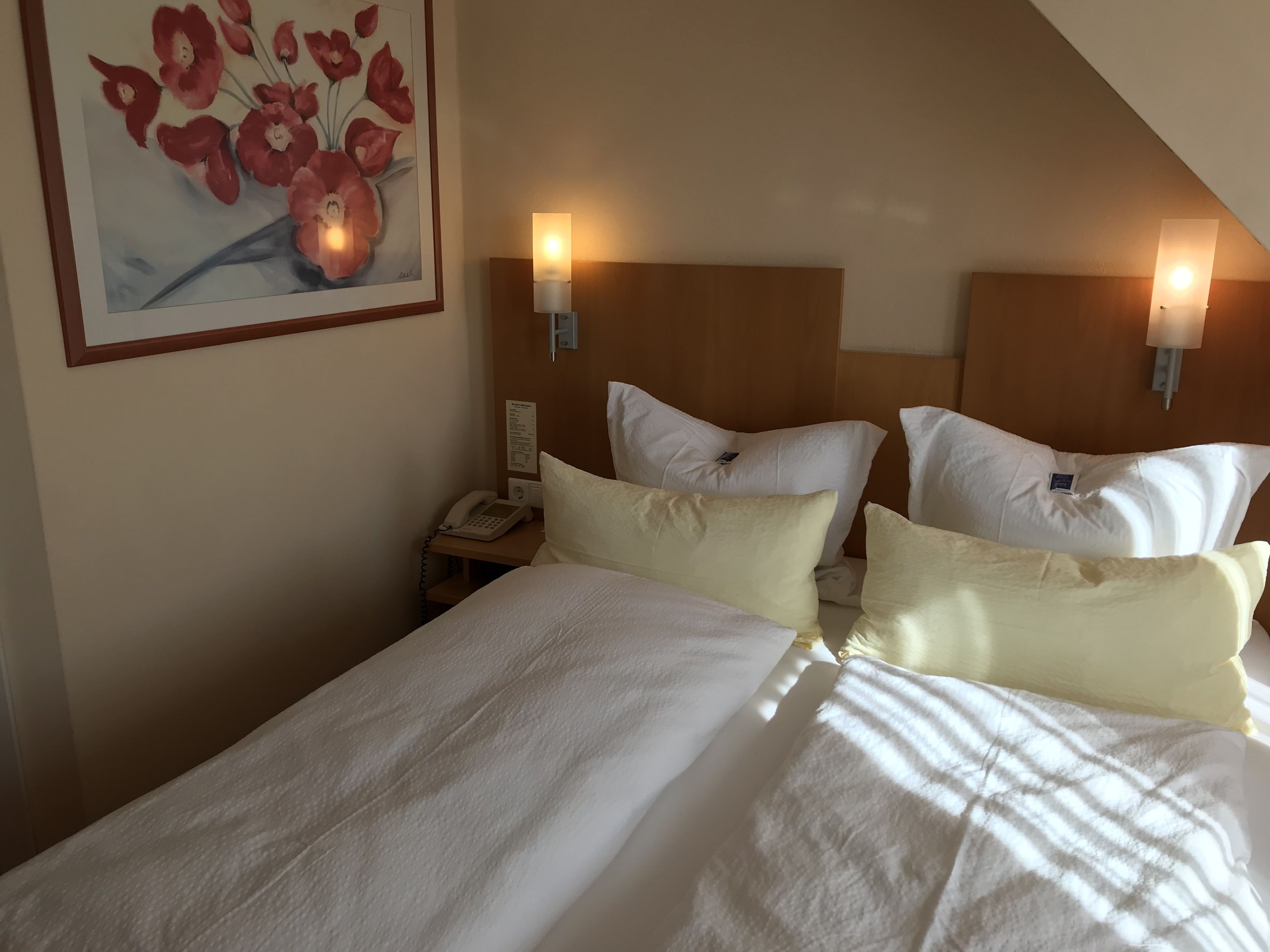 A hotel room with a large bed, two bedside tables, a phone, and wall-mounted lamps.