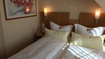 A hotel room with a large bed, two bedside tables, a phone, and wall-mounted lamps.