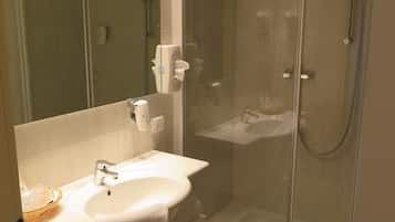 Ein modernes Badezimmer mit einer Duschkabine, einem Waschbecken mit Handtuchhalter und einem Spiegel über dem Waschbecken.