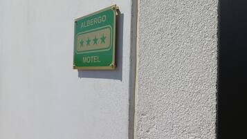A green sign with "ALBERGO MOTEL" and three stars indicating a three-star rating.