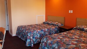 A room with two beds, each with floral-patterned bedding, a wooden headboard, and a small bedside table. - Travel Lite Motel (Wytheville)