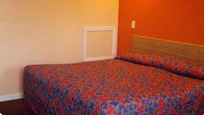 A room with a bed, a wooden headboard, and a wall with a light switch. - Travel Lite Motel (Wytheville)
