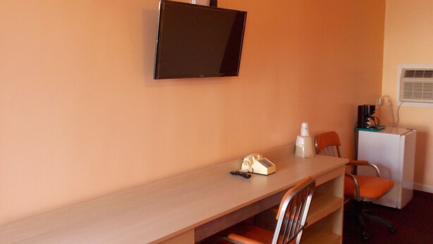 A small office with a desk, chair, and a flat-screen TV mounted on the wall. - Travel Lite Motel (Wytheville)