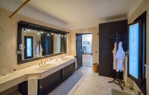 A modern bathroom with a double sink vanity, a large mirror, and a walk-in shower.