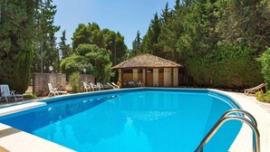 Una piscina con sillas de descanso y un pabellón.