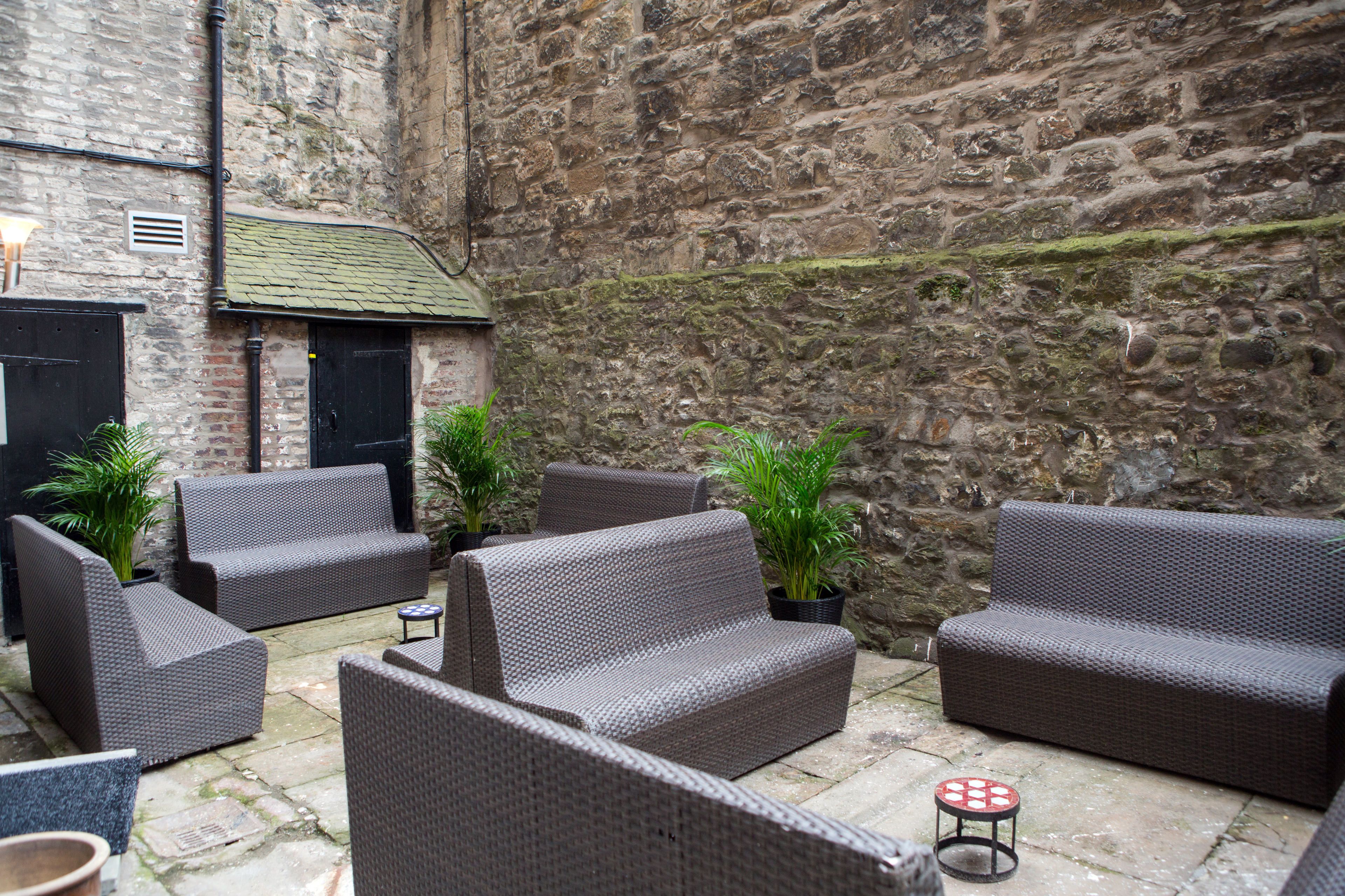 A courtyard with wicker furniture, potted plants, and stone walls.