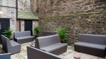 A courtyard with wicker furniture, potted plants, and stone walls.