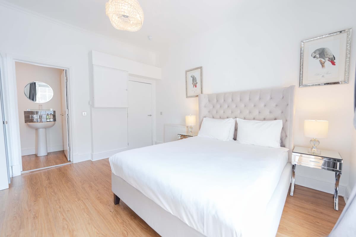 A bedroom with a large bed, bedside tables, a mirror, and a framed picture on the wall.