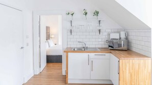 Una cocina moderna con armarios blancos, encimera de madera y una cafetera.
