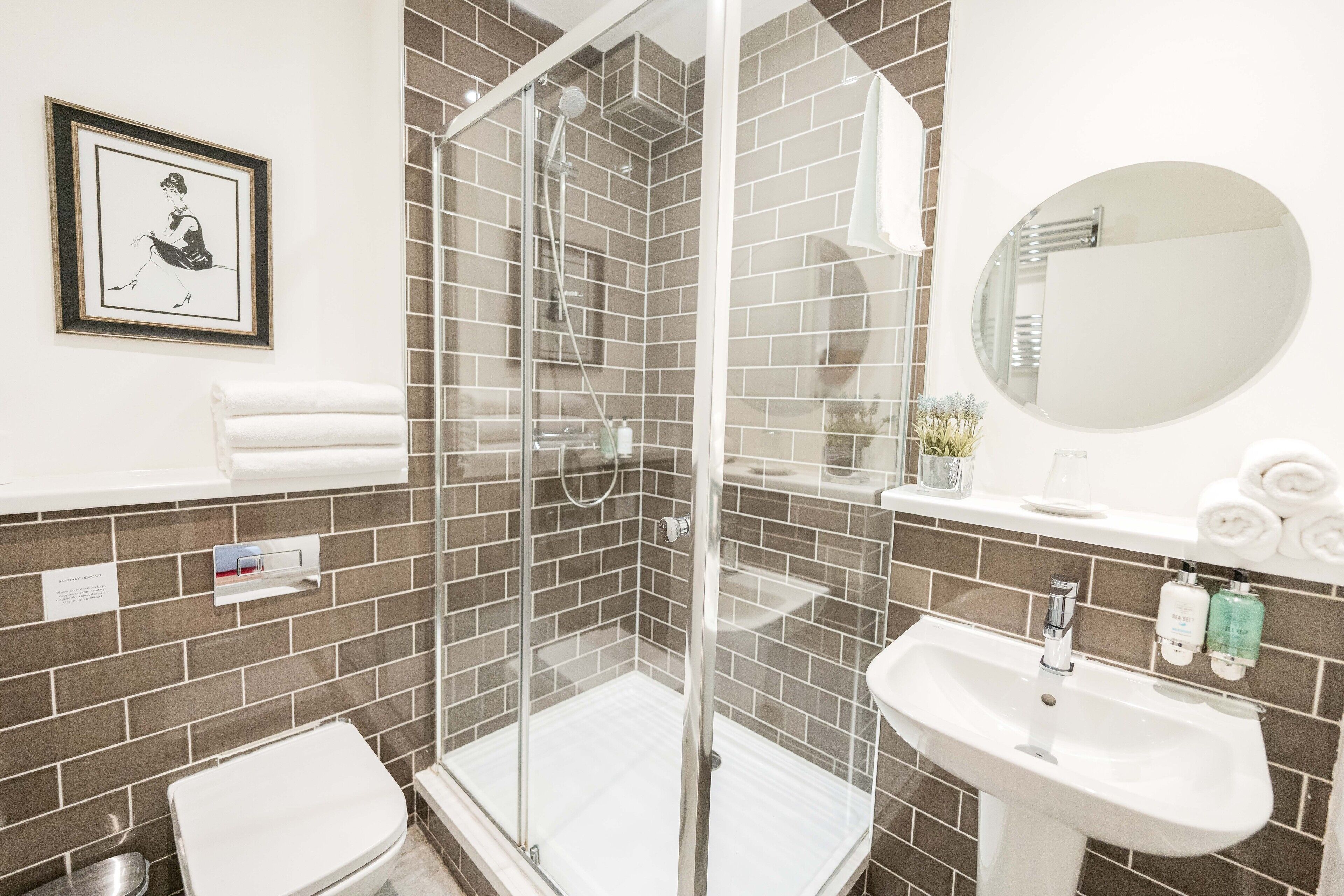 A bathroom with a glass-enclosed shower, a sink, and a mirror.