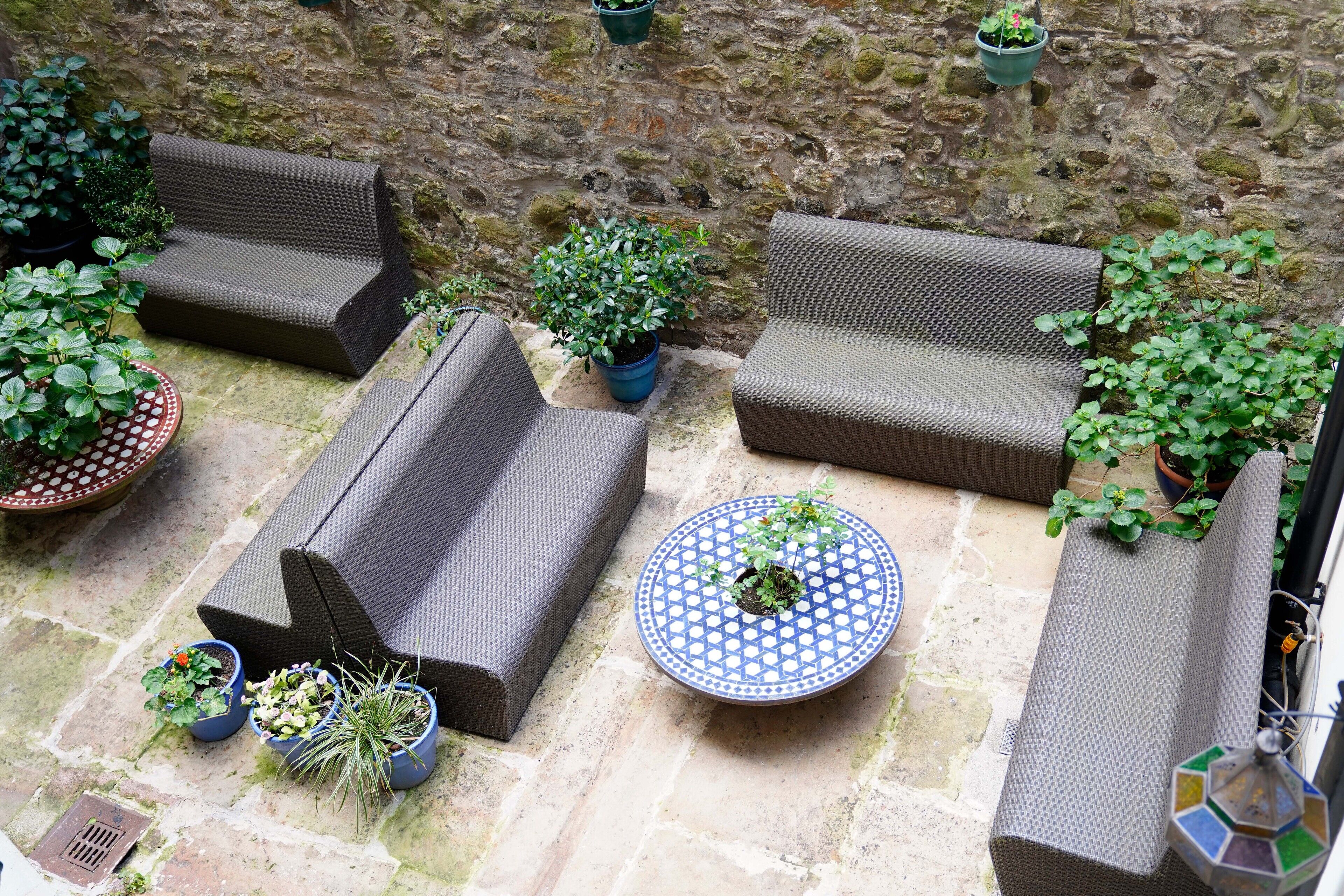 Un espacio al aire libre con mobiliario de mimbre y plantas en macetas.