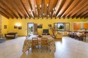 Amplia sala de estar con mesa de comedor, sillas, sofá y televisión.