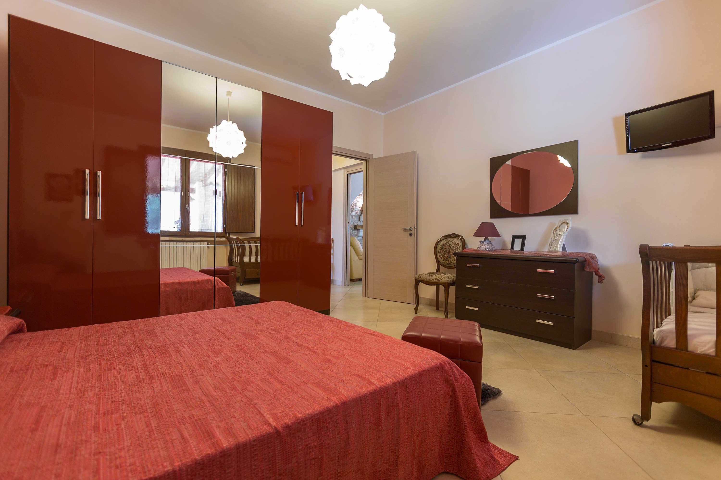 A bedroom with a bed, a dresser, a mirror, and a television.