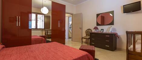 A bedroom with a bed, a dresser, a mirror, and a television.