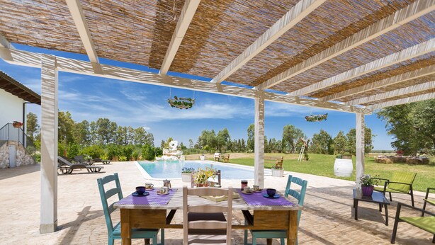 An outdoor patio with a pool, covered seating, and a view of the pool and greenery. - Villa Pizzi (San Donaci)