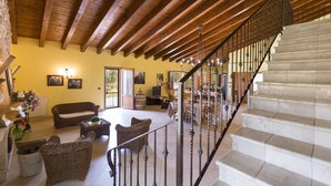 A spacious living area with a wooden ceiling, a staircase, and a dining area with a table and chairs. - Villa Pizzi (San Donaci)