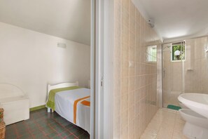 Un dormitorio con cama, mesita de noche y armario. Incluye un baño con inodoro, ducha y lavamanos.