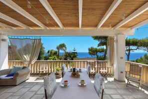 Une terrasse avec une table dressée pour le dîner, offrant une vue sur la mer.