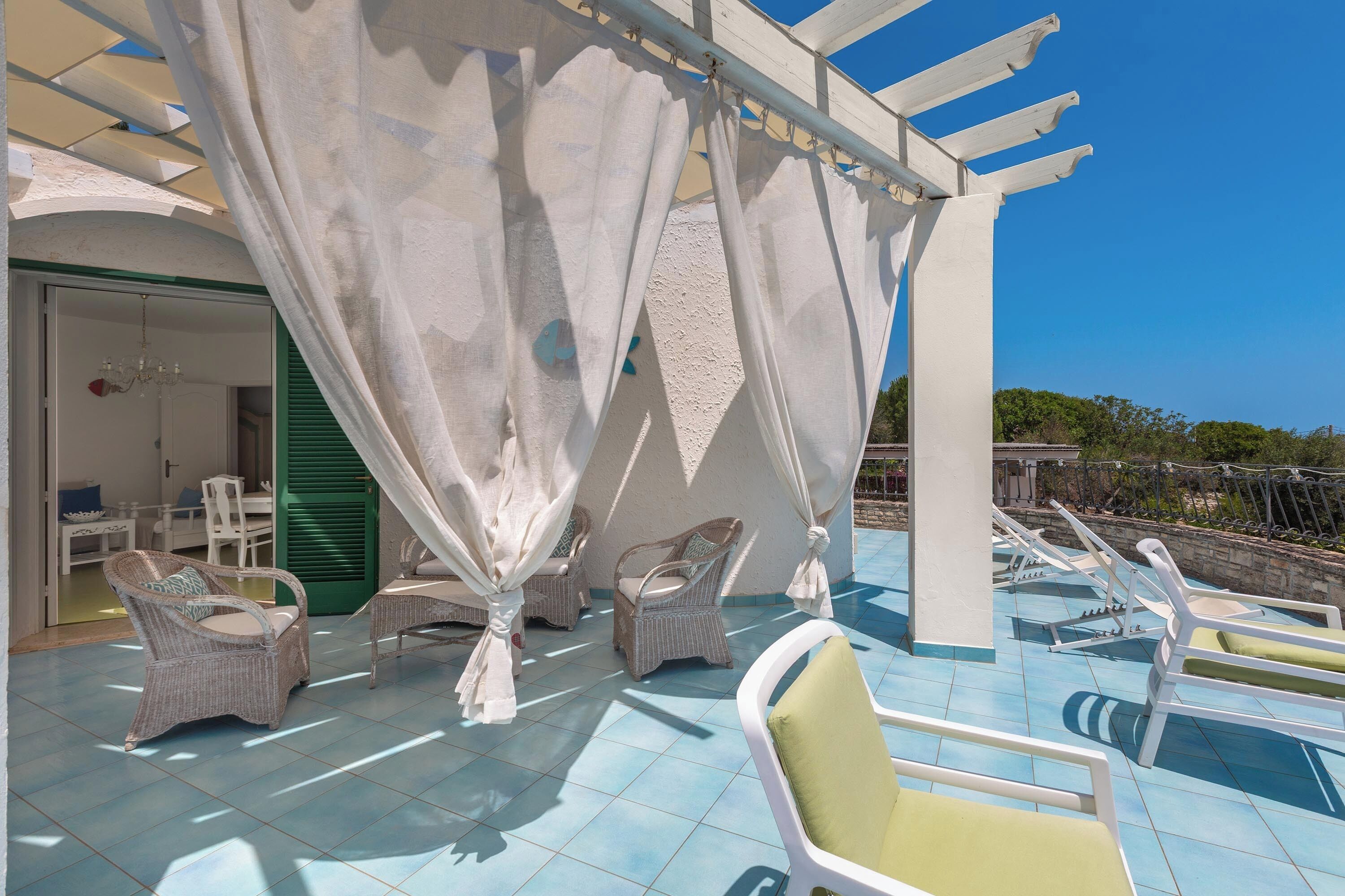 A sunlit outdoor seating area with wicker chairs and a pool.