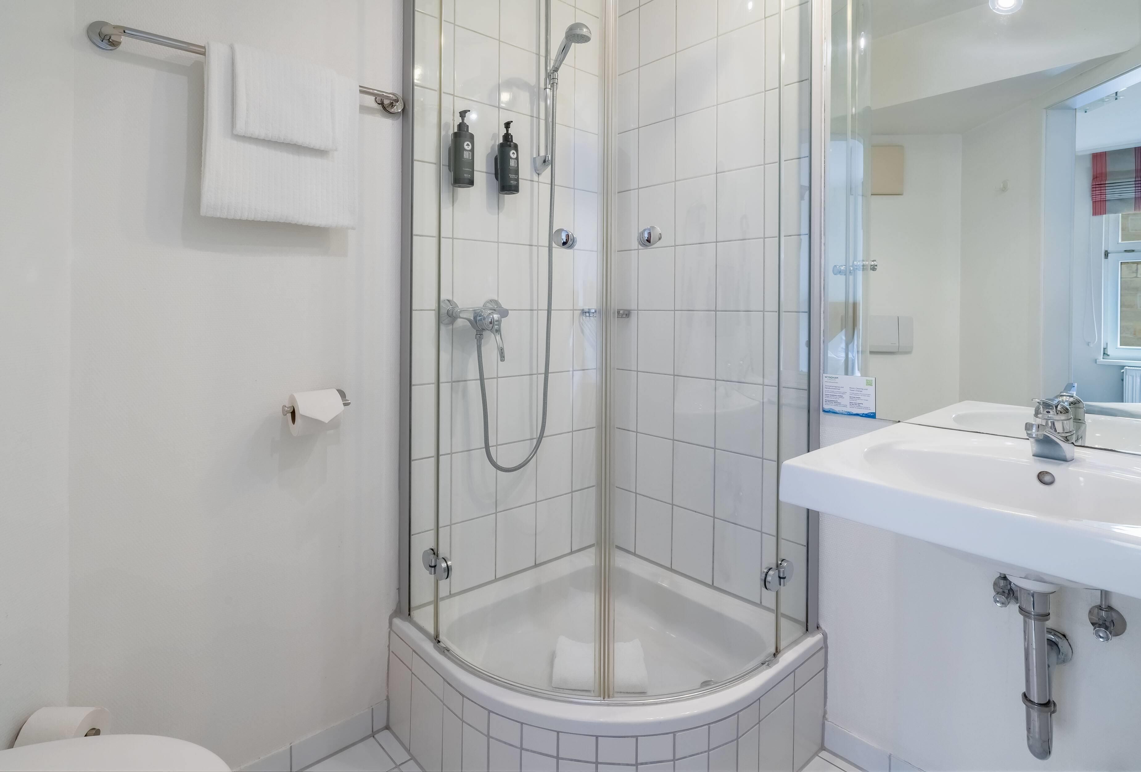 A modern bathroom with a glass-enclosed shower, a white sink, and a toilet.