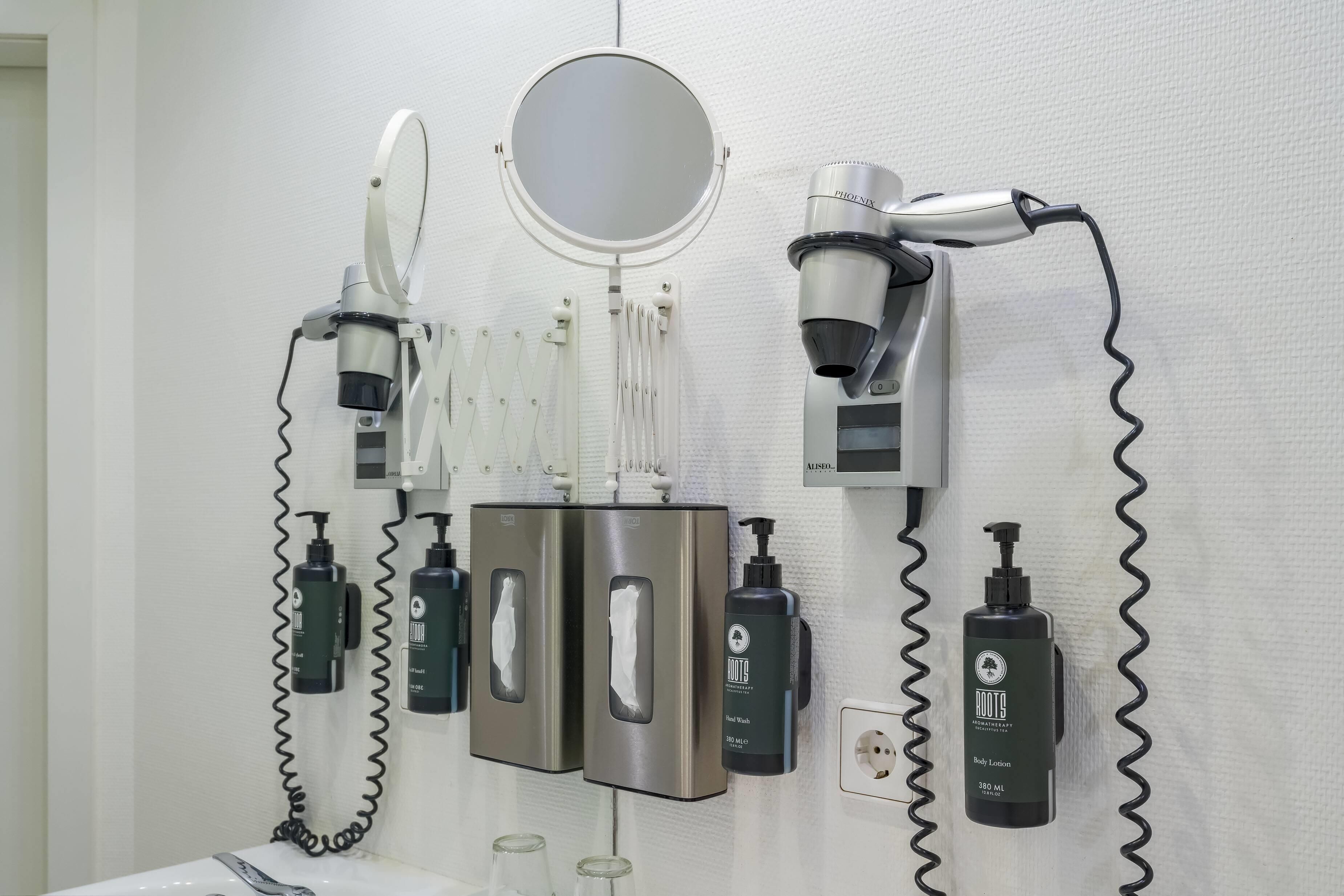 Un baño con secador de pelo, espejo y distintos artículos de aseo.
