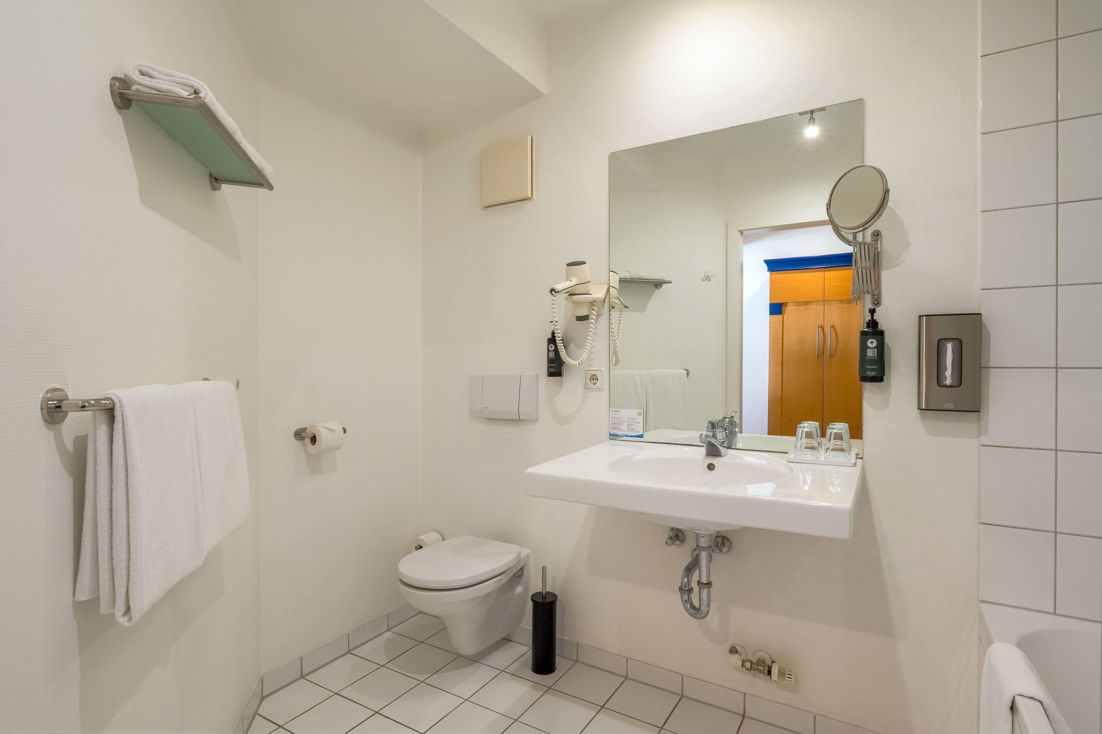 A modern bathroom with a toilet, sink, and mirror.
