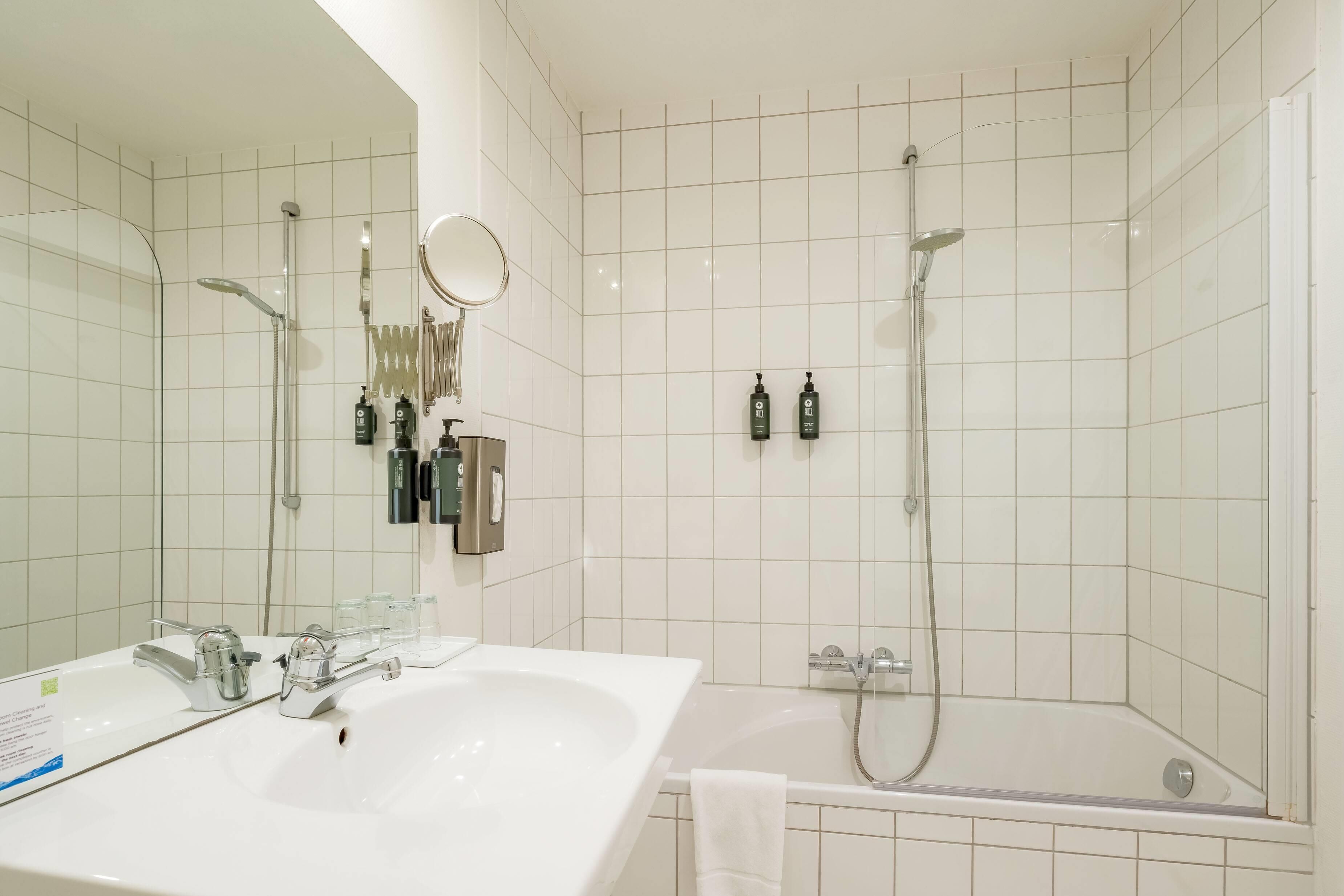 A modern bathroom with a large white sink, a bathtub, and a shower area.