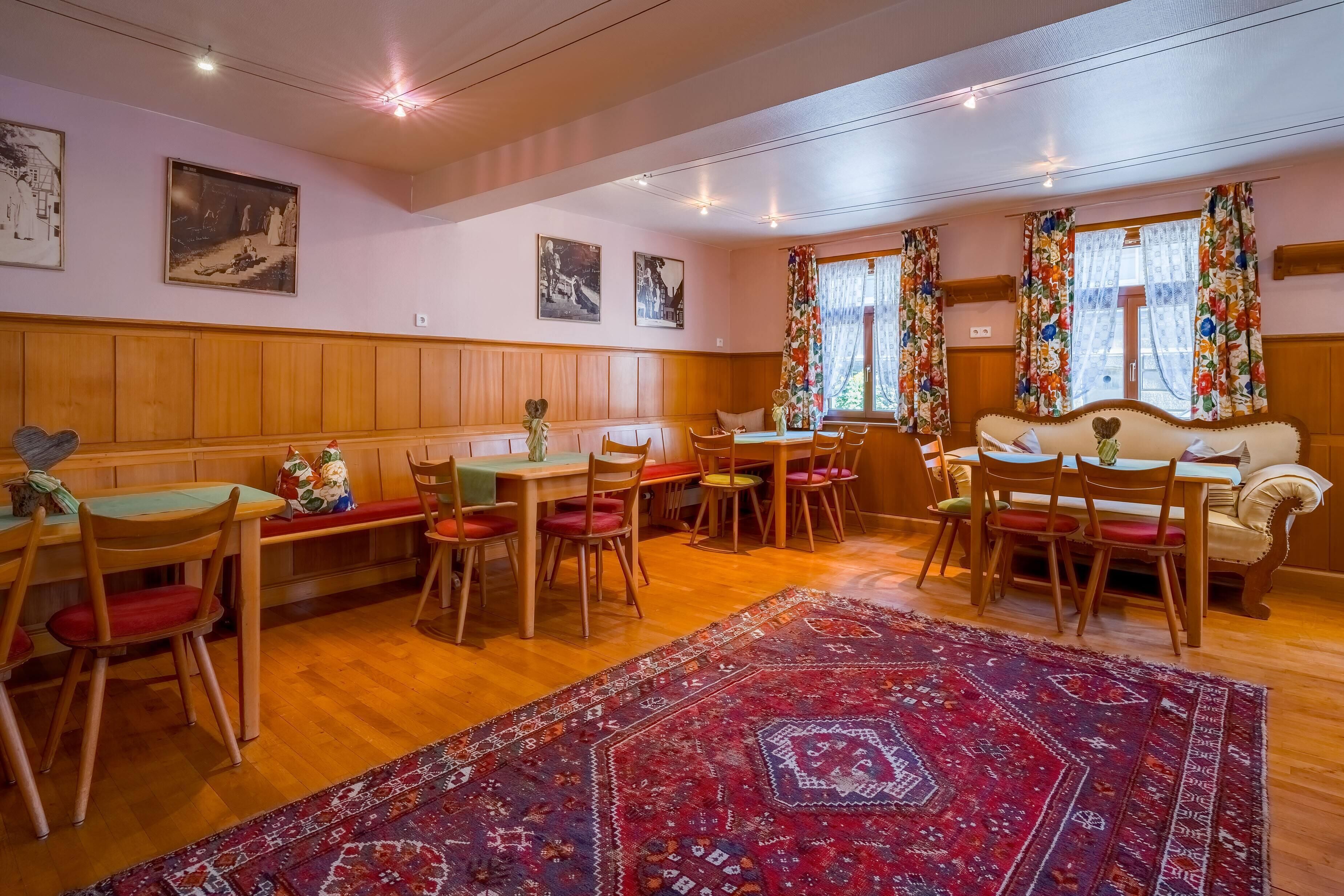A dining area with wooden furniture, a patterned rug, and artwork on the walls.