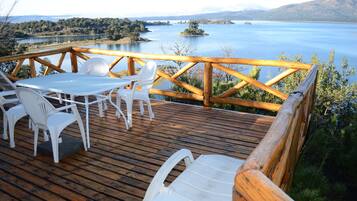 A wooden deck with a table and chairs overlooking a lake.