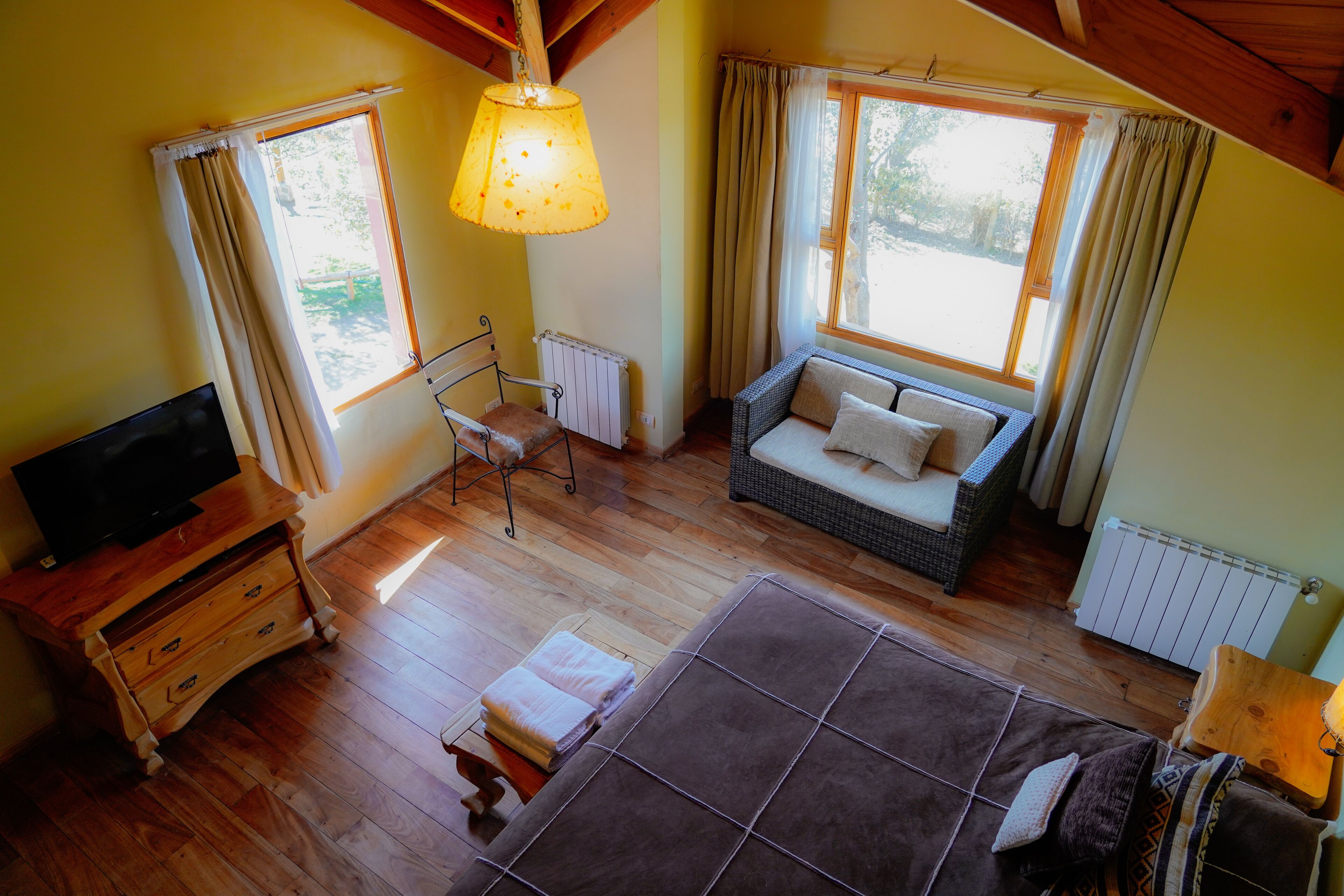 A cozy room with a sofa, a television, and a window with curtains.