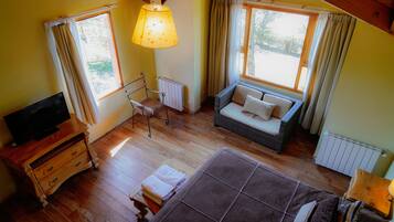 A cozy room with a sofa, a television, and a window with curtains.